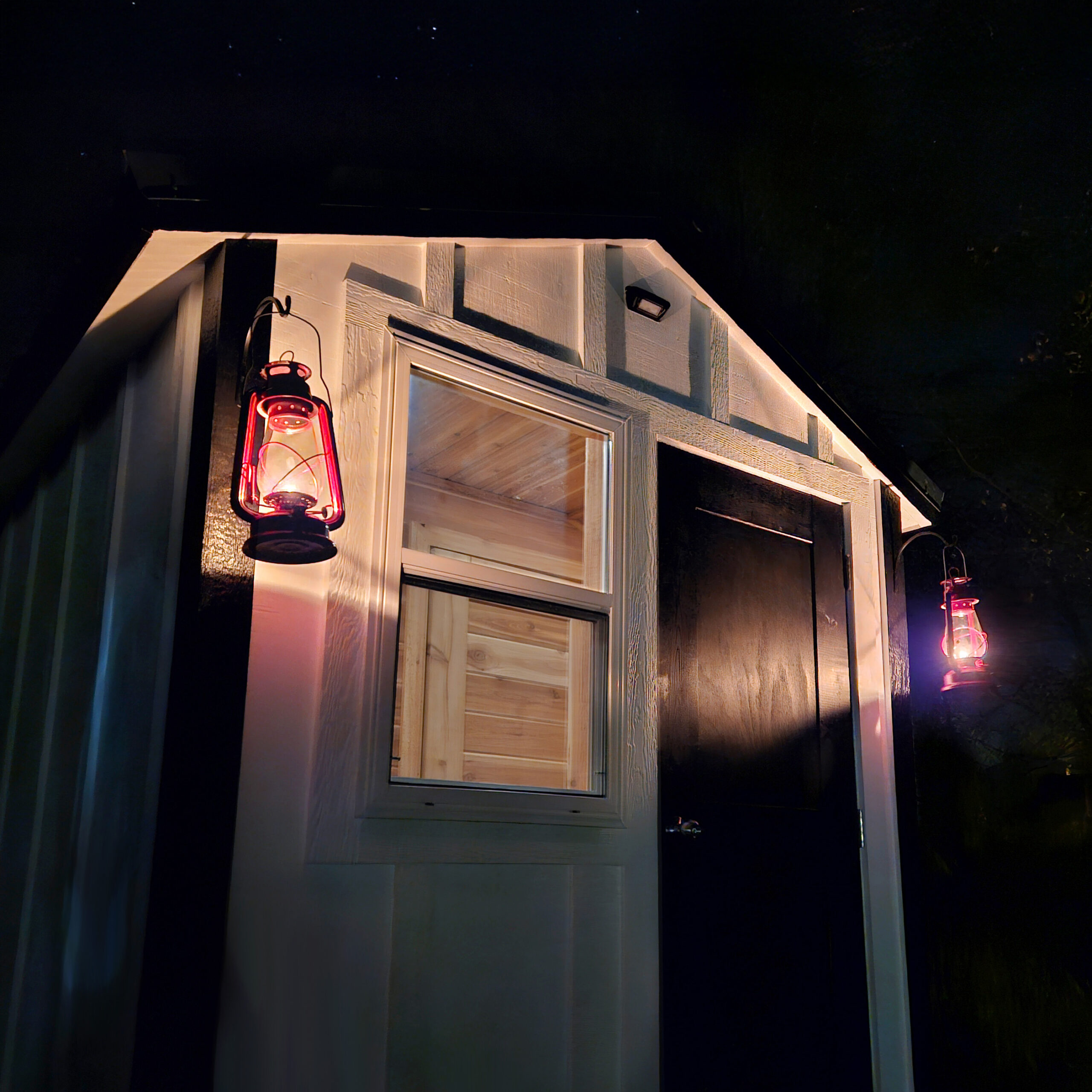 Rear view at night with oil lanterns illuminating the sauna.