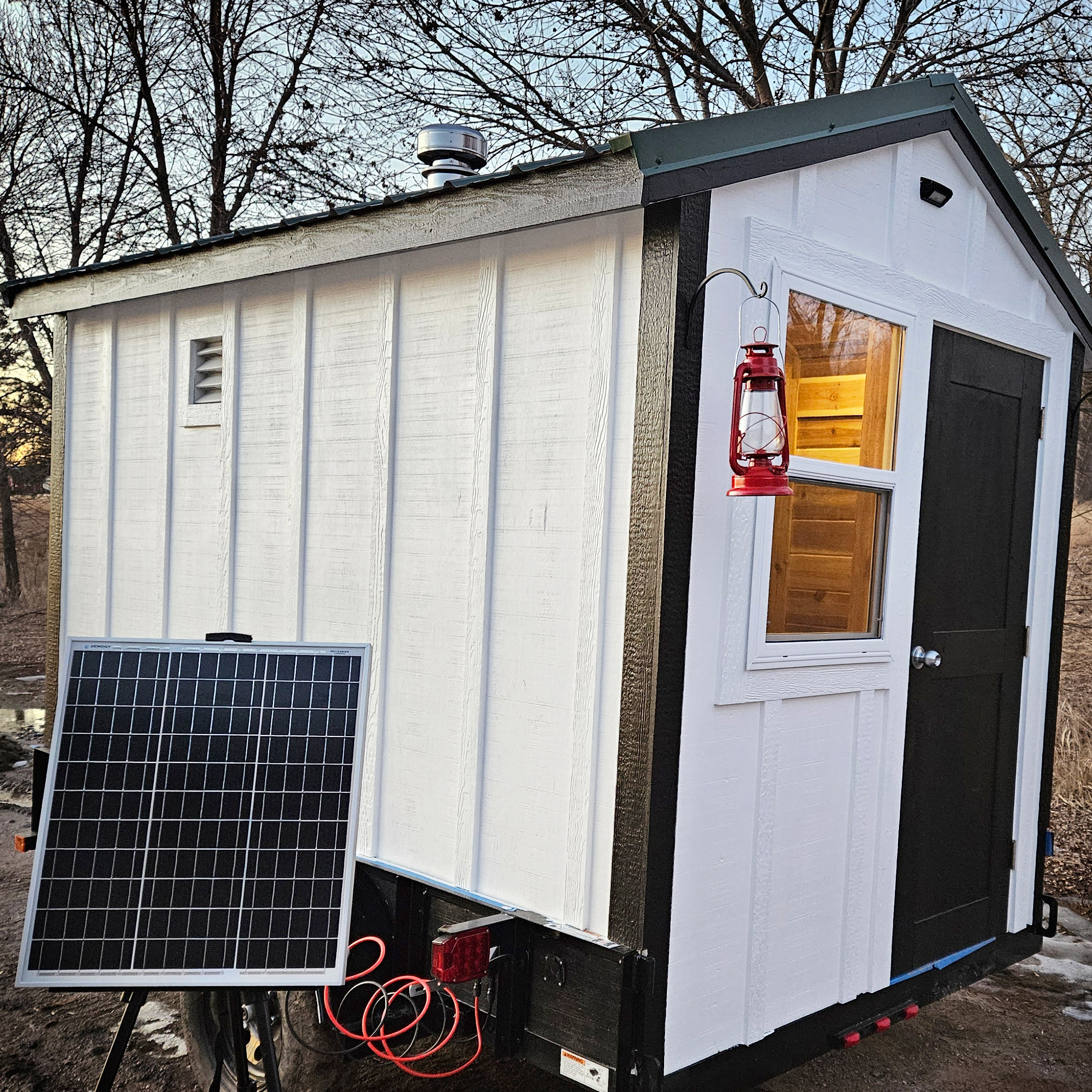 Off-grid sauna with solar panel and lantern.