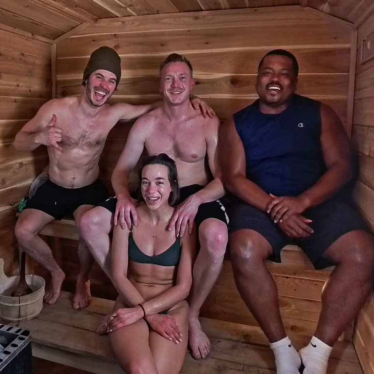 Four friends laughing and enjoying a wood-fired session inside a cedar-lined Minnesota Mobile Sauna.